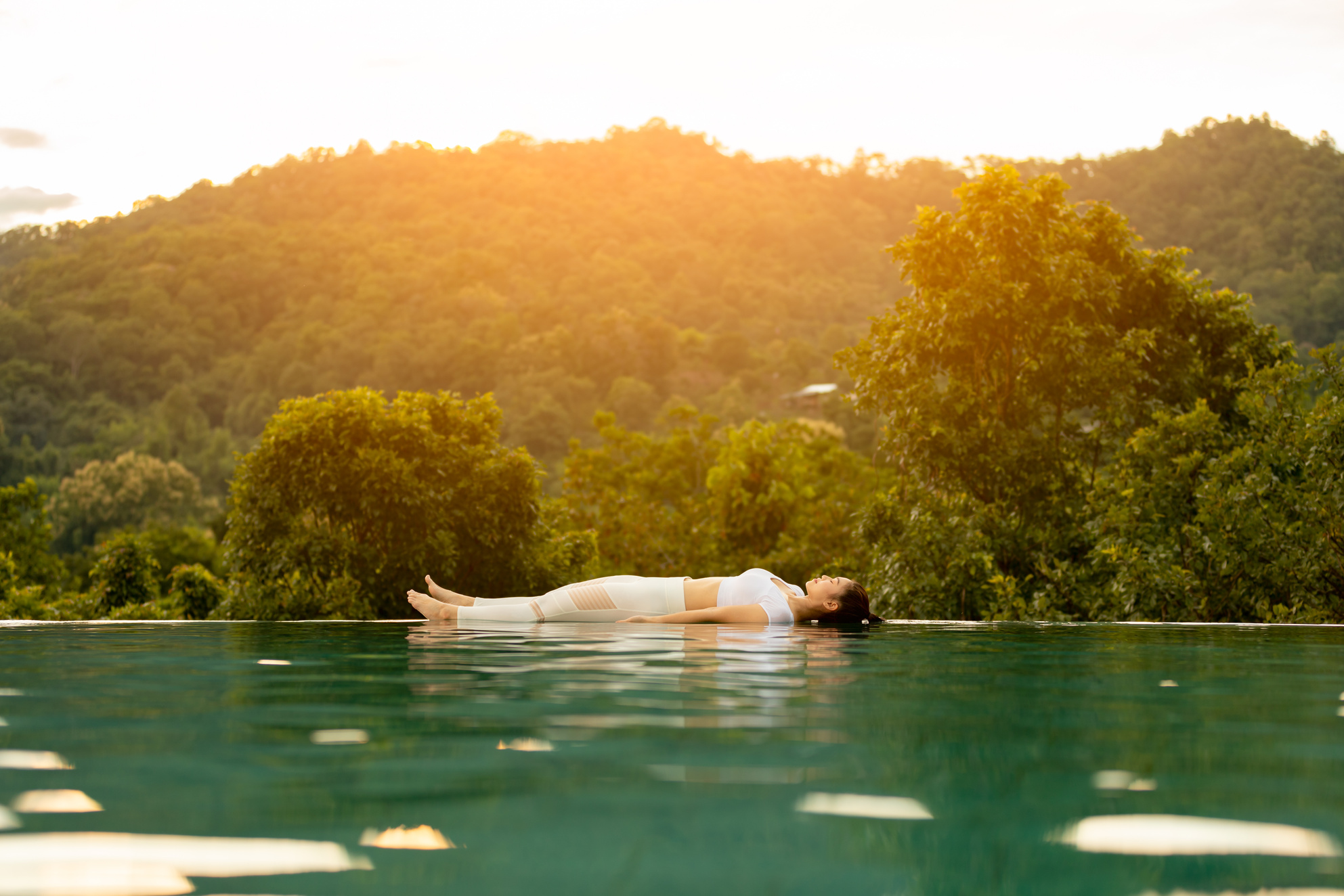 Asian woman practice yoga Dead Body or Savasana pose on the pool above the Mountain peak in front of beautiful nature views,comfortable and relax in vacations